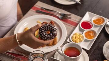 A table set with breakfast items including a plate of fruit, muffins, and a donut.