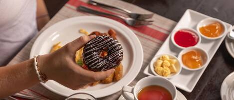 A table set with breakfast items including a plate of fruit, muffins, and a donut.