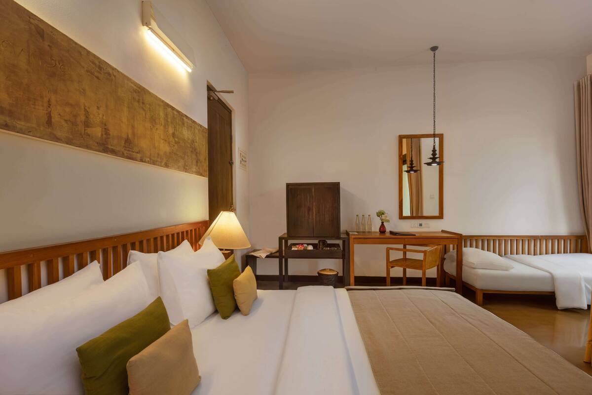 A hotel room with a large bed, a desk with a chair, a television, and a mirror.