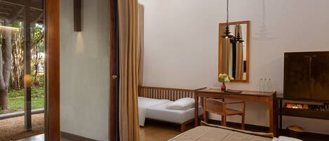 A hotel room with a bed, a desk, a chair, a TV, and a sliding glass door leading to an outdoor area.