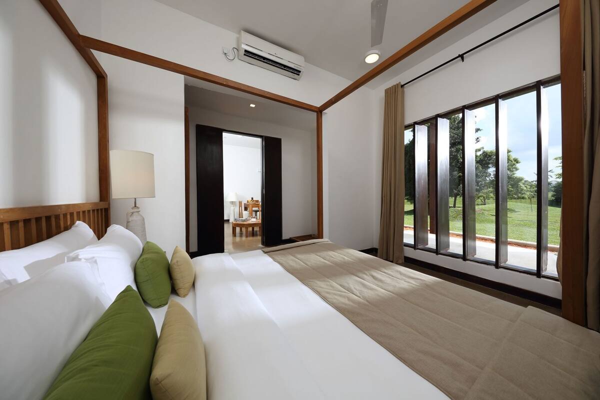 A hotel room with a large bed, a desk, a chair, and a view of the outdoors.