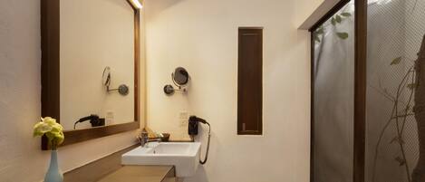 A modern bathroom with a large mirror, a sink, and a shower.