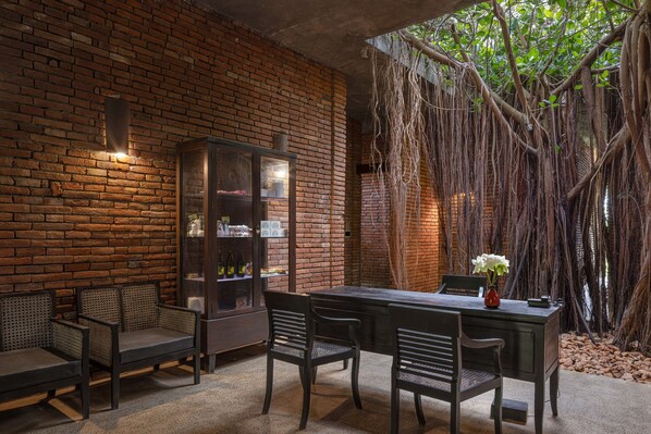 A brick wall, wooden chairs, a table, and a glass cabinet. - Sigiriya Jungles (Avudangawa)