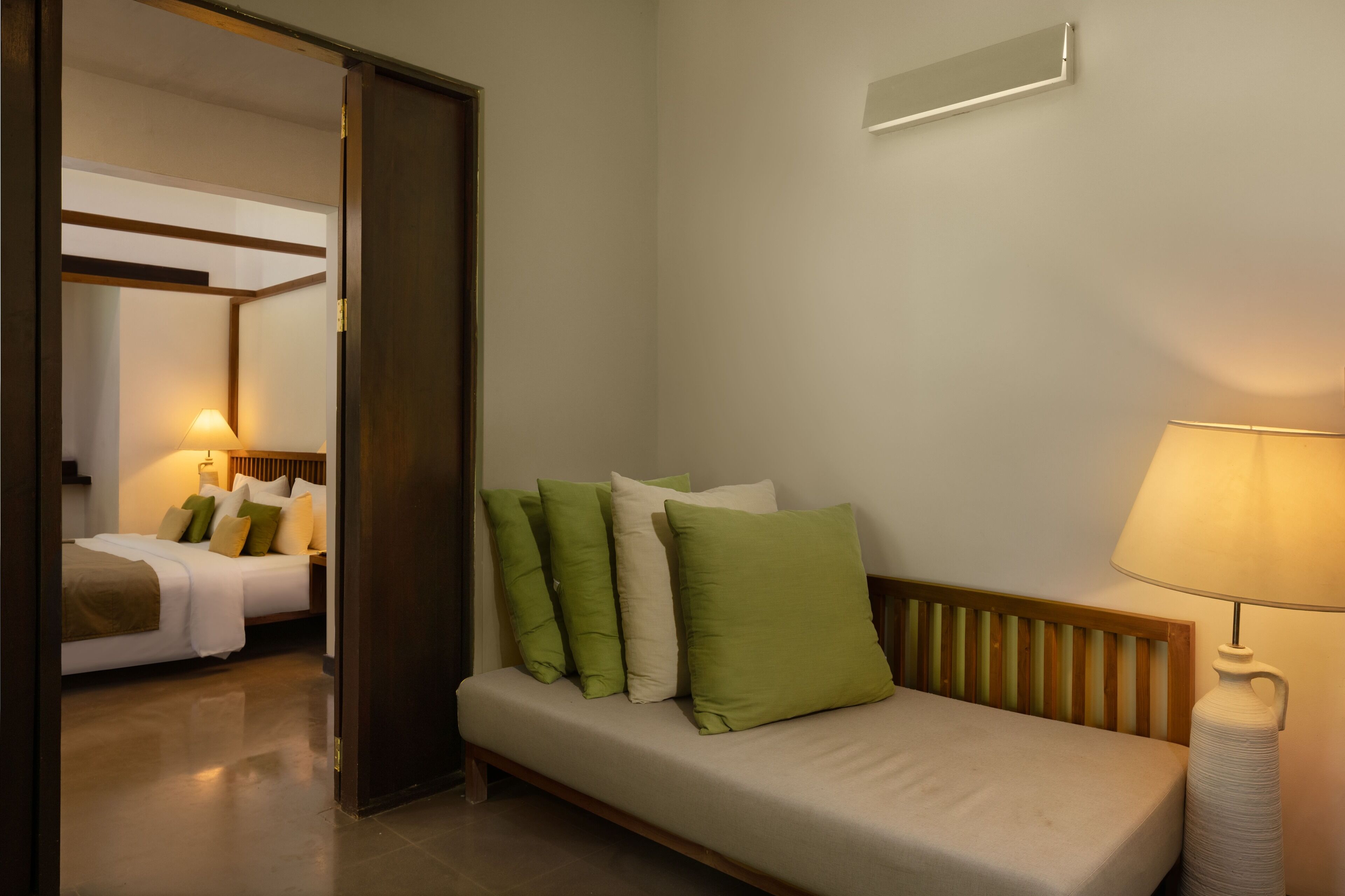Une chambre d’hôtel avec un lit, un canapé, une lampe et un luminaire fixé au mur.