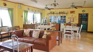 Amplia sala de estar con un sofá de cuero marrón, una mesa de comedor con sillas y una cocina al fondo.