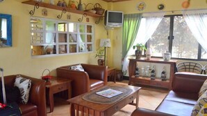 Una sala de estar acogedora con un sofá de cuero marrón, una mesa de centro de madera y un televisor sobre un mueble.