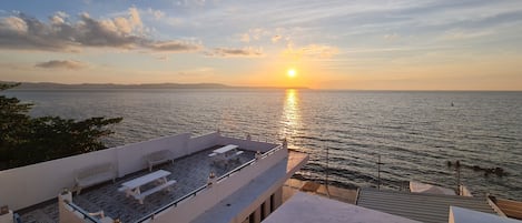 A sunset view from a rooftop terrace with a pool and outdoor seating.