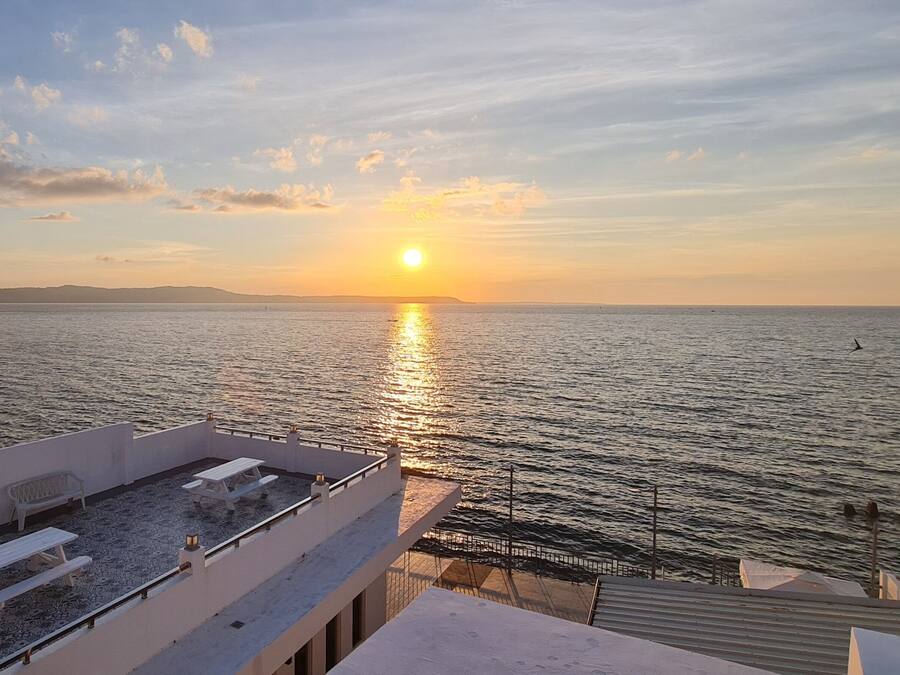 Vista del atardecer desde una terraza en la azotea con piscina y mobiliario exterior.