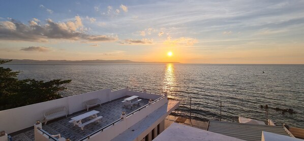 A sunset view from a rooftop terrace with a pool and outdoor seating.