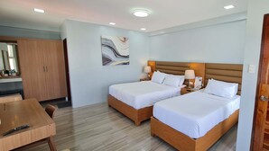 Habitación de hotel con dos camas, un armario de madera, un escritorio y un espejo.