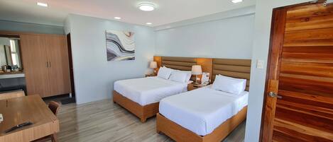 Habitación de hotel con dos camas, un armario de madera, un escritorio y un espejo.