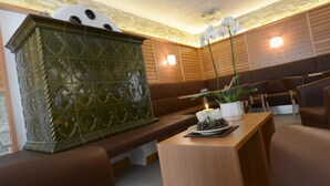 A reception area with a wooden bench, a reception desk, and a decorative cabinet. - Cimon Dolomites Hotel (Predazzo)