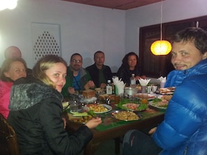 A group of people seated around a table with various dishes and drinks. - New Annapurna Guest House (Pokhara)