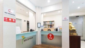 Zona de recepción con un cartel de 'No Fumar', un mostrador de recepción y una estatua.