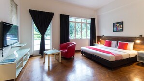 Una habitación de hotel con cama, escritorio, computadora, silla y televisor.