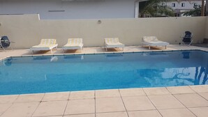 A swimming pool with four lounge chairs and a tiled deck. - Hôtel Saint Jacques - Centre Ville (Pointe-Noire)