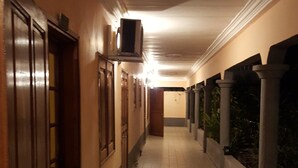 A corridor with tiled flooring, wooden doors, and a ceiling with a light fixture. - Hôtel Saint Jacques - Centre Ville (Pointe-Noire)