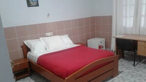A bedroom with a wooden bed, a nightstand, a desk, and a small cabinet. - Hôtel Saint Jacques - Centre Ville (Pointe-Noire)