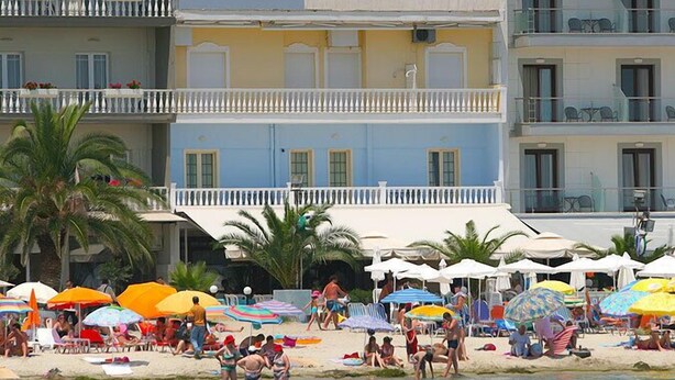 A beachside hotel with multiple balconies, outdoor seating, and umbrellas. - Hotel Zografos (Katerini)