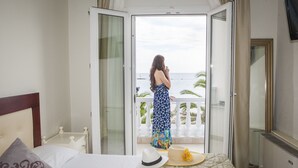 A hotel room with a bed, a nightstand, a hat, and a straw hat on the balcony. - Hotel Zografos (Katerini)