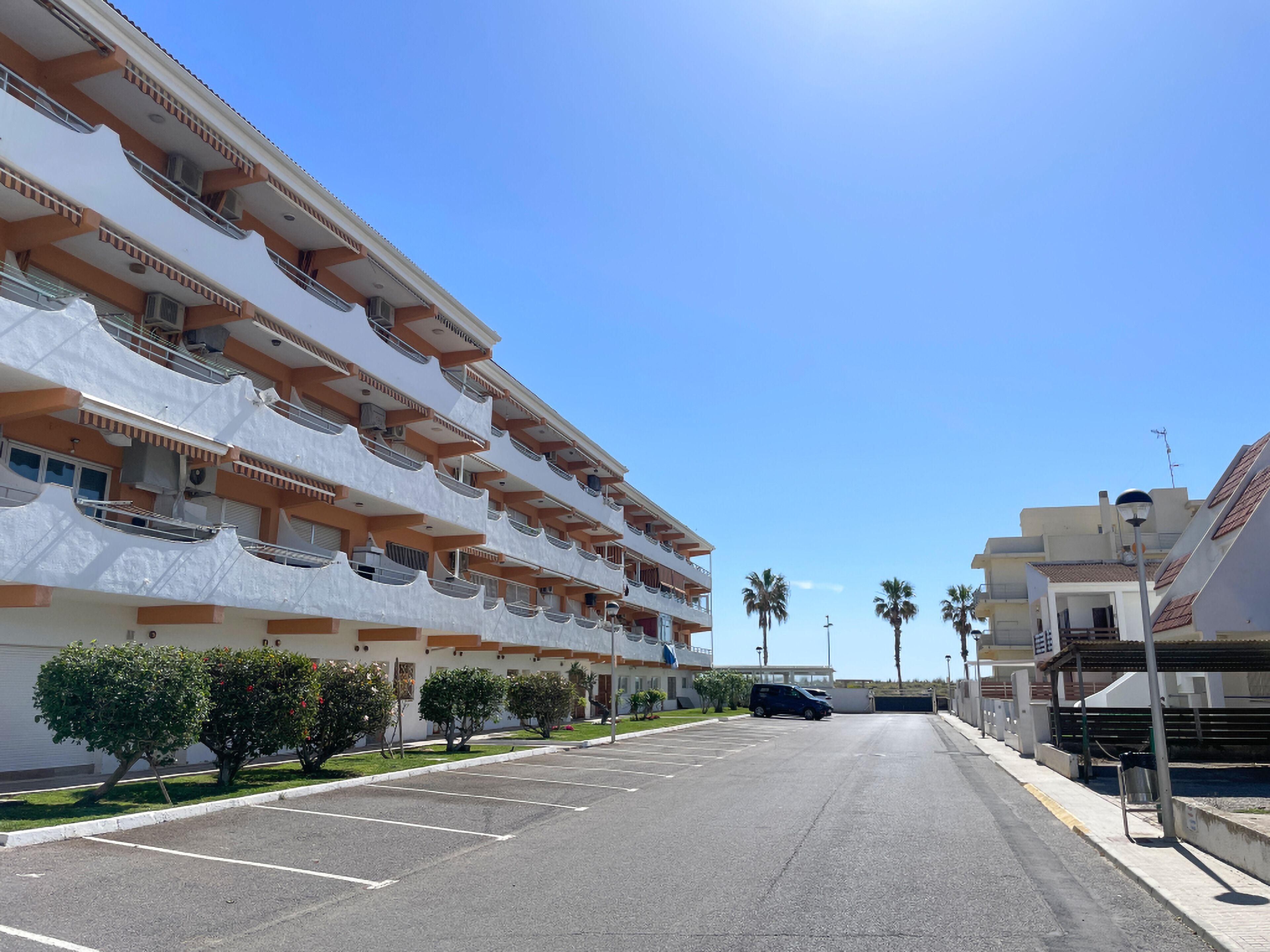 Un hôtel à plusieurs étages doté de balcons, d’un parking et de palmiers.
