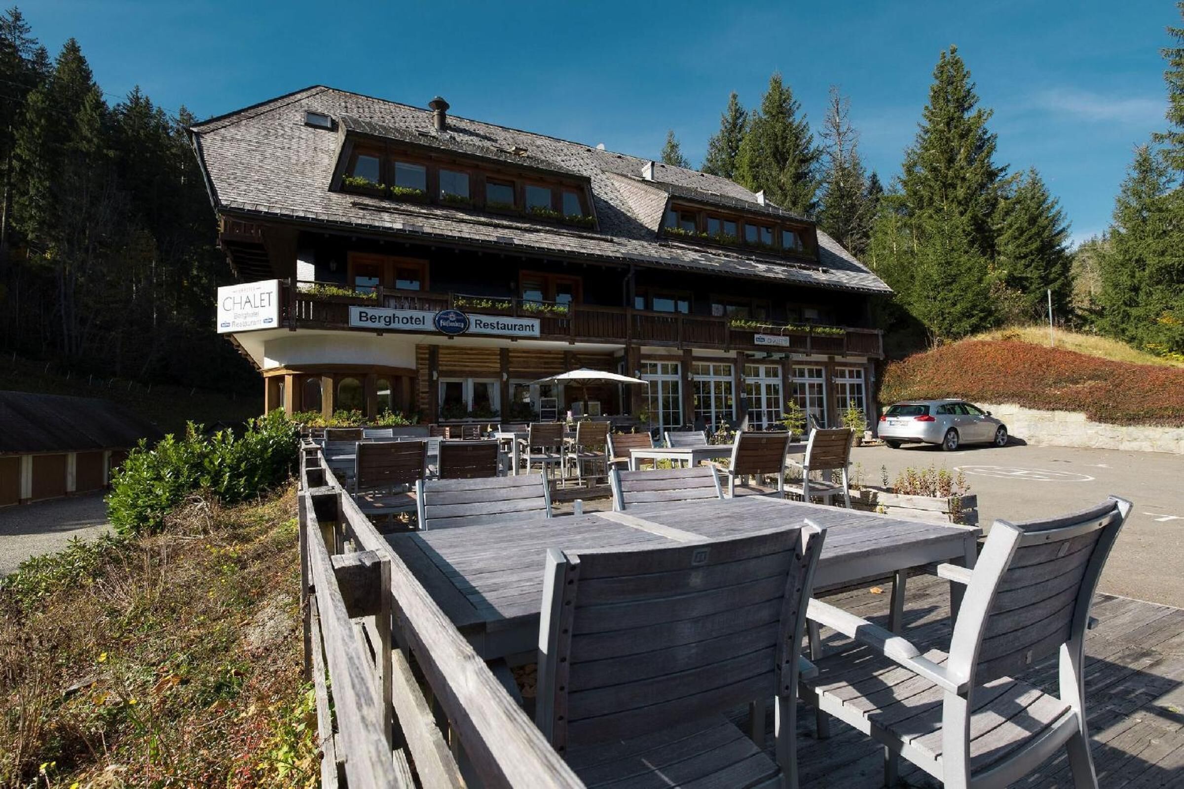 Ein Chalet-Stil-Gebäude mit Außenbestuhlung und einem Schild, das Restaurant und Hotel anzeigt.