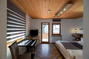 A compact room with a wooden ceiling, a bed, a TV, a desk, and a chair. - Kräuter Chalet (Furtwangen)