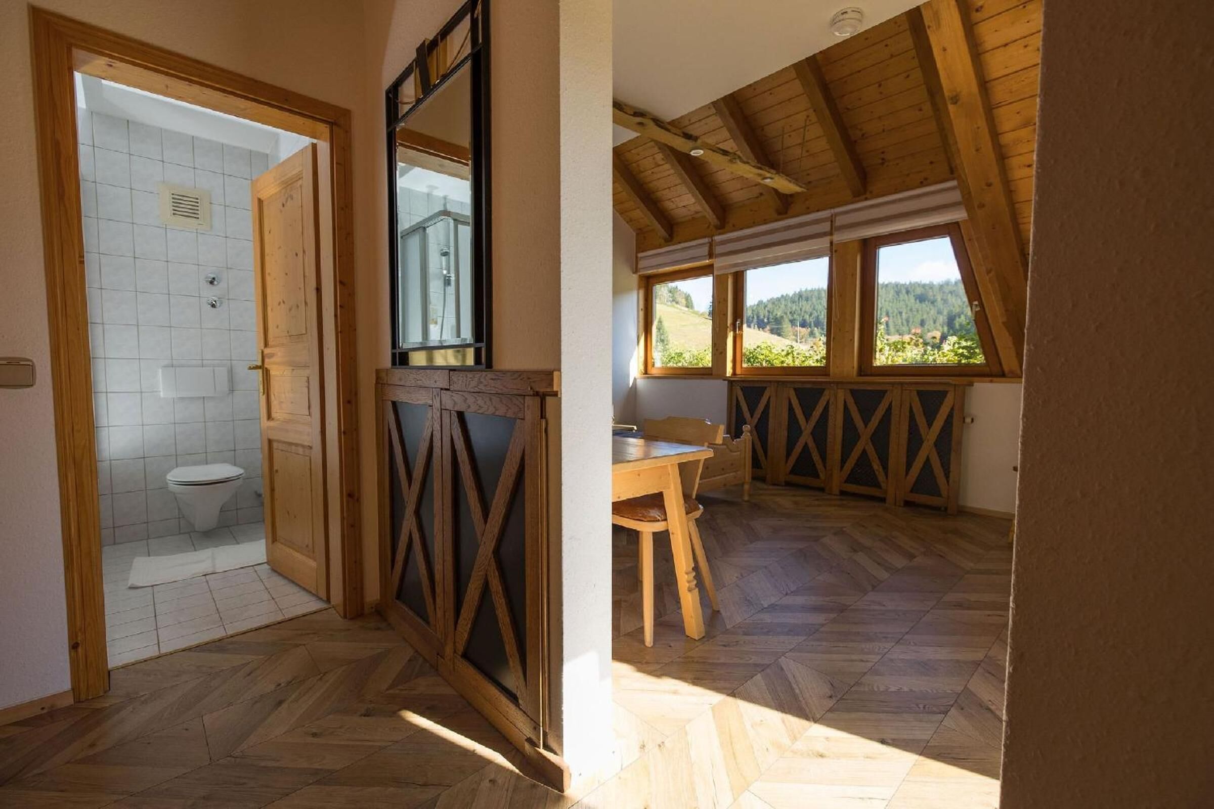 A rustic bathroom with a wooden door, a tiled shower area, and a herringbone floor pattern.
