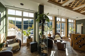 A spacious room with large windows, a glass display cabinet, and a wine rack. - Kräuter Chalet (Furtwangen)