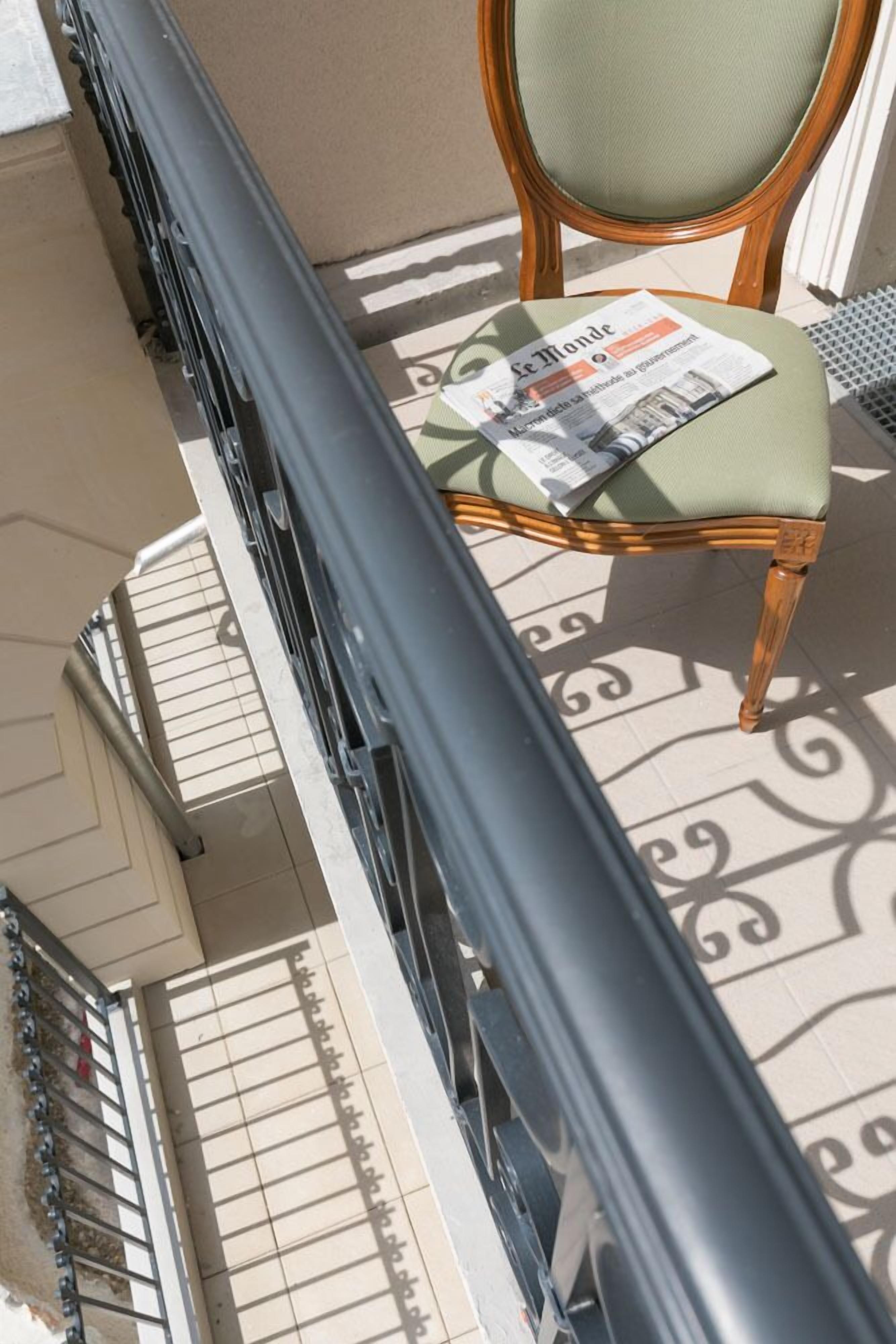 A balcony with a chair and a newspaper.