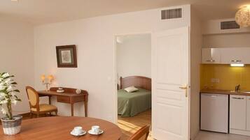 A compact hotel room with a dining area, a kitchenette, and a bed.