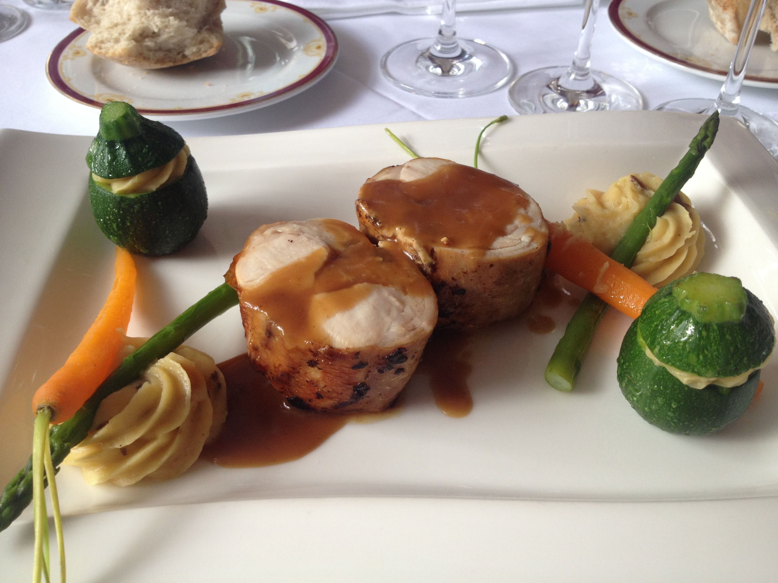 A plated dish with vegetables and a piece of meat, possibly chicken, with sauce.