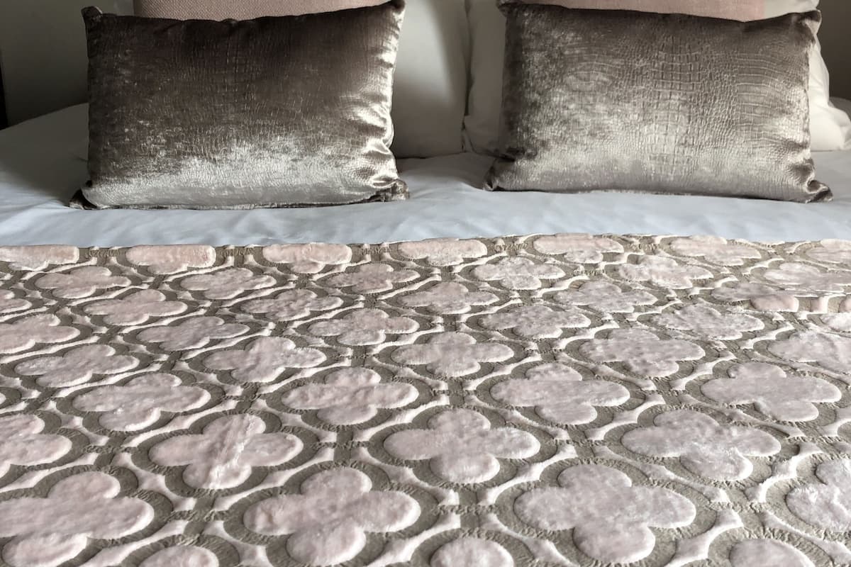 A bed with a patterned blanket and two pillows.
