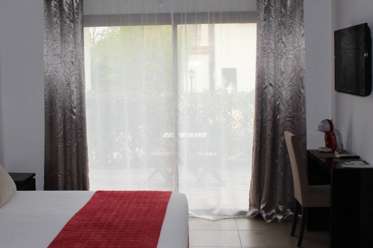 A hotel room with a bed, a desk, and a chair.