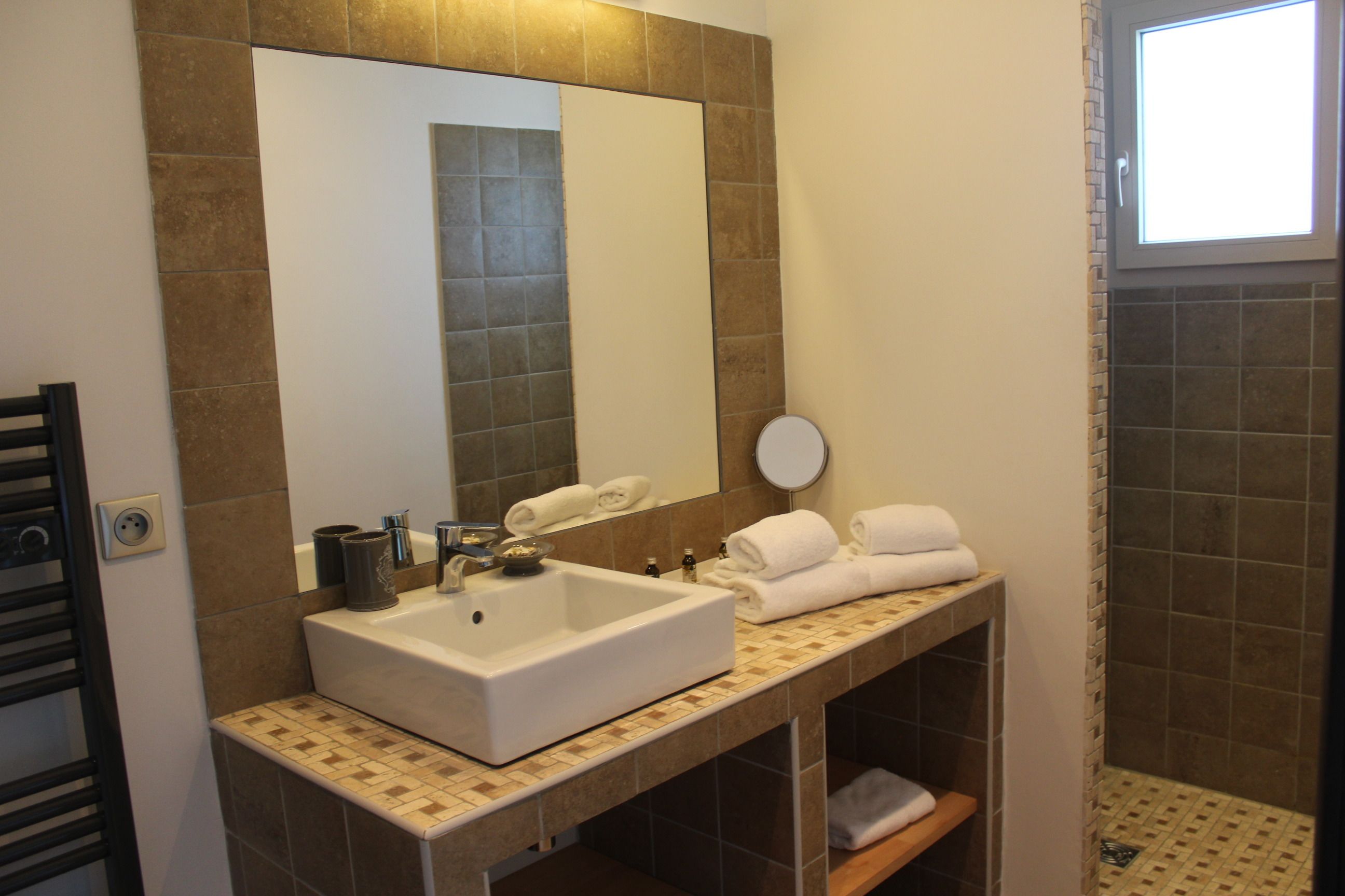 A bathroom with a large mirror, a sink, and a shower area.