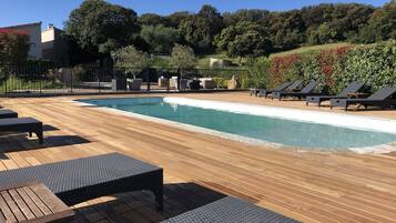 Relax by the serene pool surrounded by lush greenery and trees.