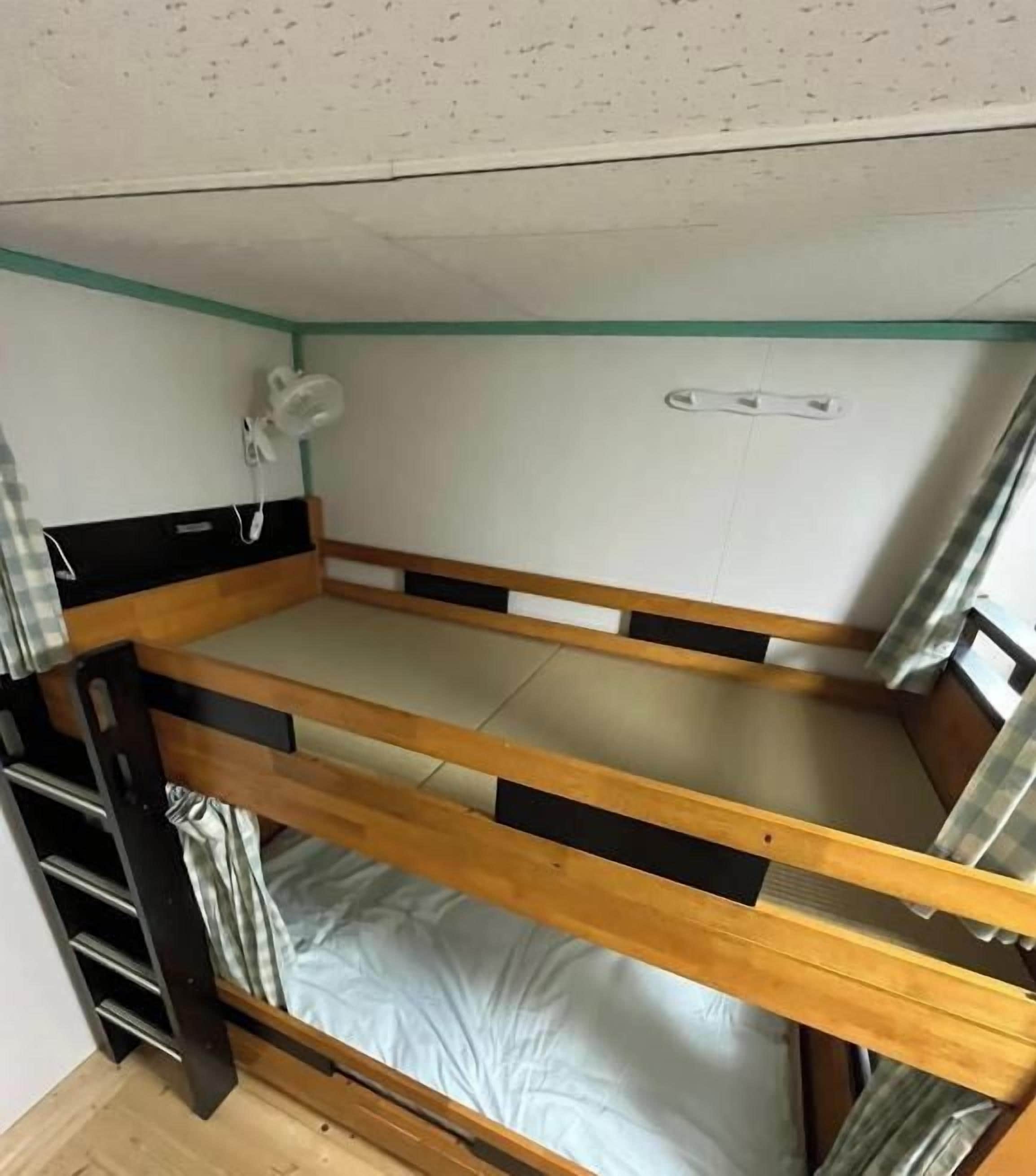 A bunk bed with a headboard, a bedside table, and a wall-mounted lamp.