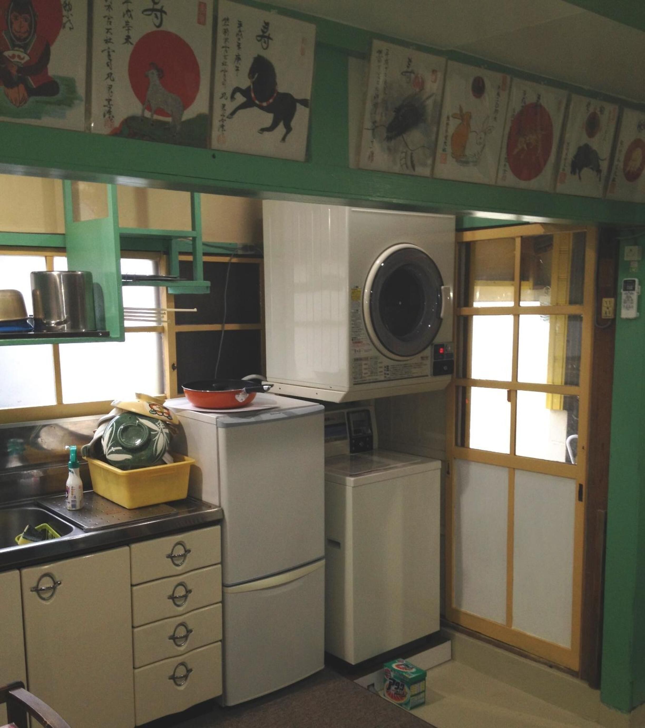 A compact kitchen with a washing machine, a sink, and a stove. There are cabinets and a window with a view.
