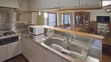 Una cocina compacta con un lavamanos de acero inoxidable, un microondas y una estufa.