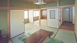 Una habitación japonesa tradicional con suelo de tatami, puertas correderas y una mesa de madera baja.