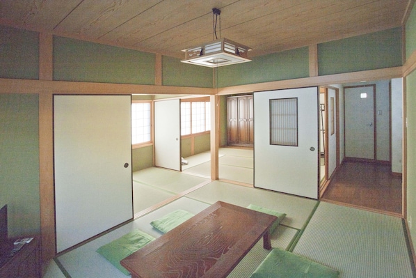 A traditional Japanese room with tatami flooring, sliding doors, and a low wooden table.