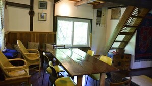 Un comedor con una larga mesa de madera, sillas de mimbre y un banco.