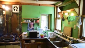 Cocina compacta con estufa a gas, microondas y pileta. Hay diferentes utensilios de cocina y recipientes en la encimera.