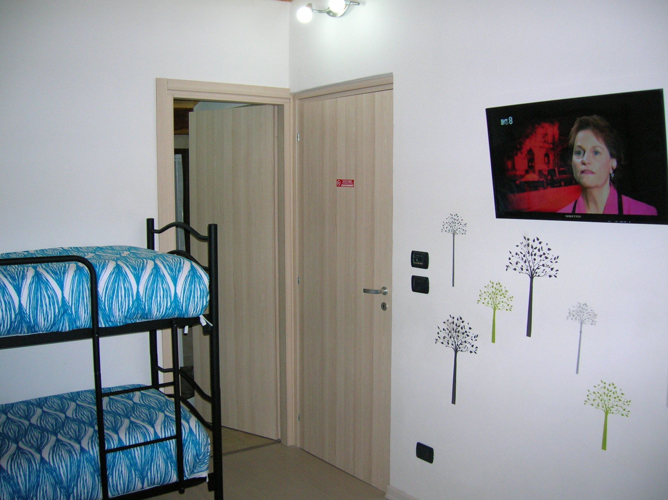 Ein Zimmer mit Etagenbetten, einer Tür und Wanddekorationen, darunter Bäume und ein Fernsehbildschirm.