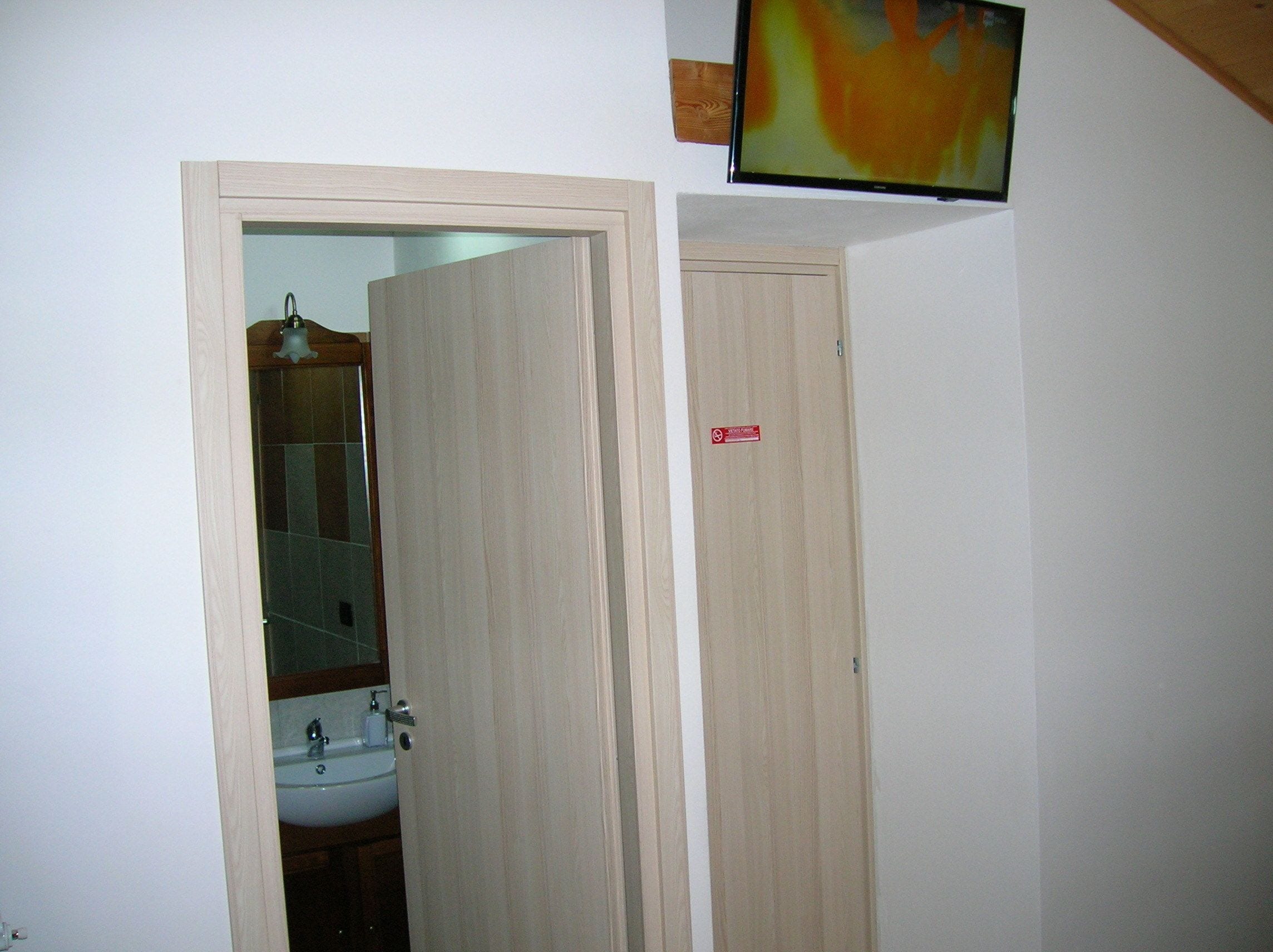 Une salle de bain avec un lavabo, un miroir et une porte ornée d’une enseigne rouge.