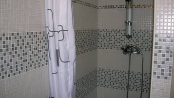 Ein Badezimmer mit Dusche, gefliesten Wänden und einer Duschvorhang.