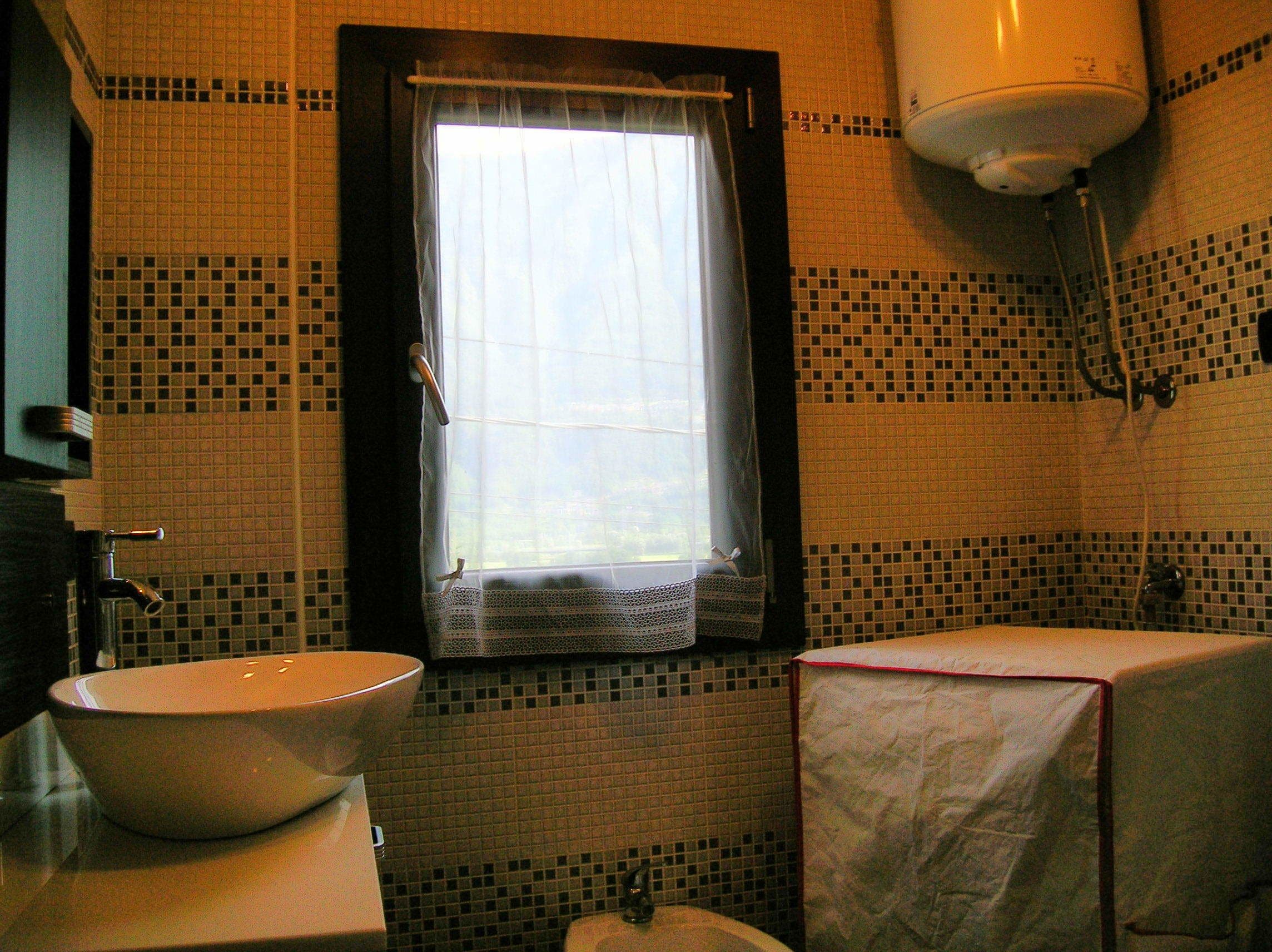 Ein Badezimmer mit Fenster, Waschbecken, Toilette und Duschbereich.