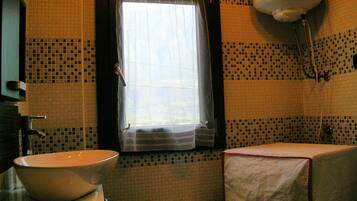 Ein Badezimmer mit Fenster, Waschbecken, Toilette und Duschbereich.
