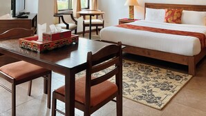 Et hotelværelse med en seng, et skrivebord med stol, et fjernsyn og et vindue med gardiner.