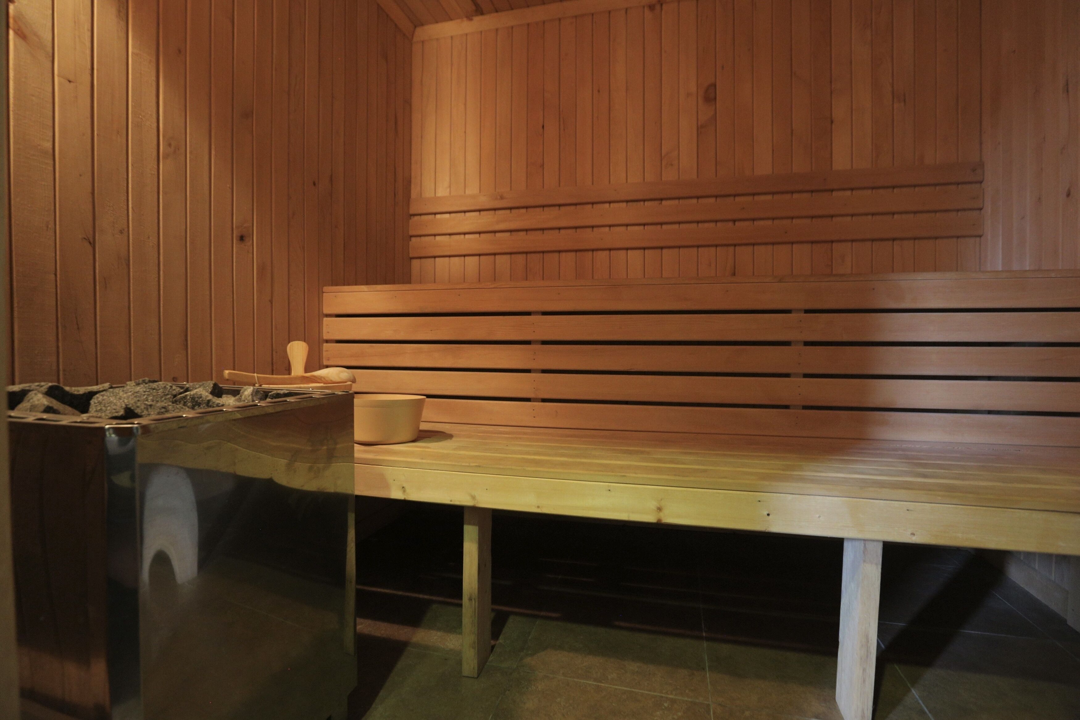 A wooden sauna with a bench and a small table with a bowl.